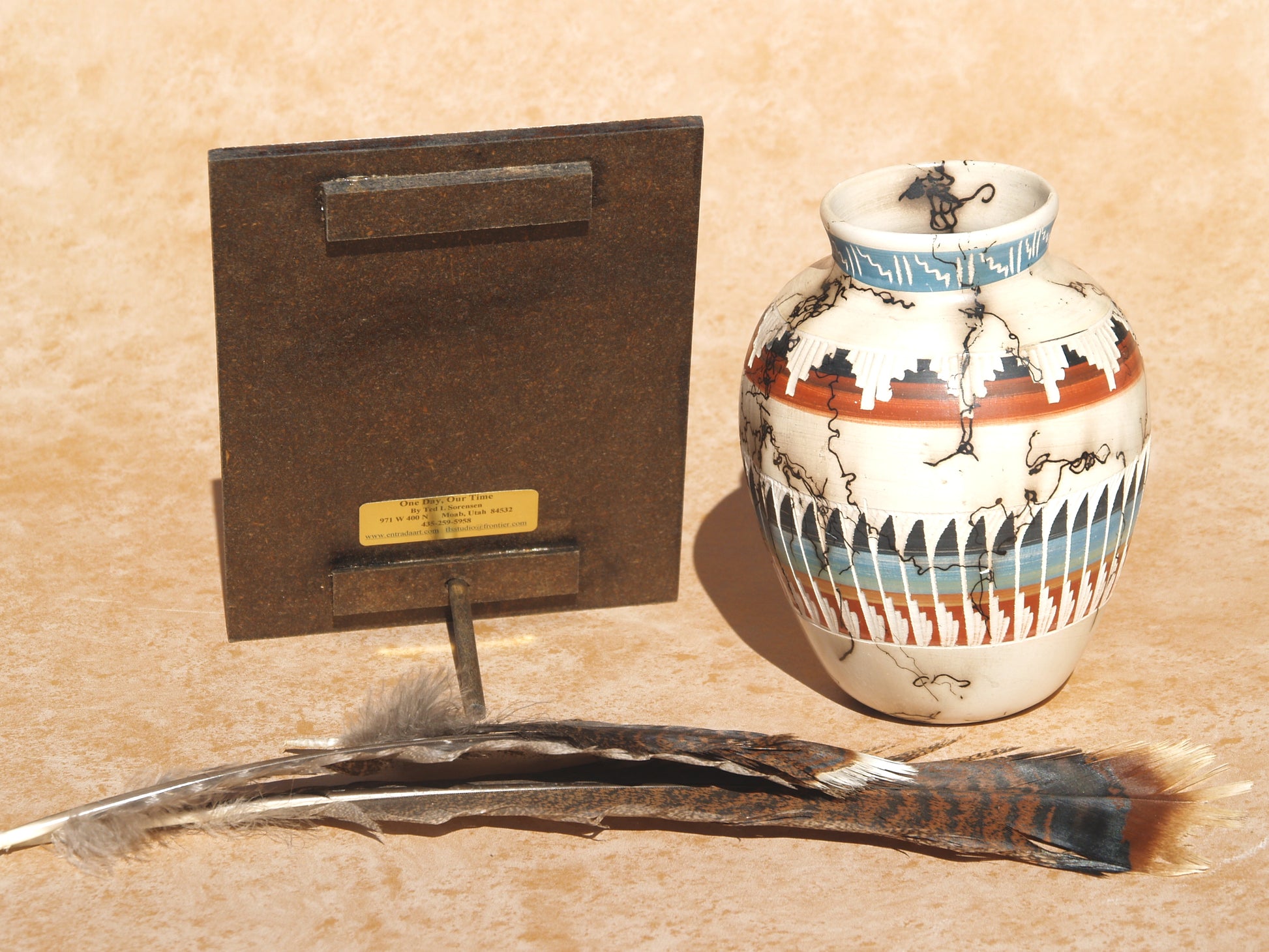 Native American art mini panel display stand with traditional pottery and feathers on tan surface