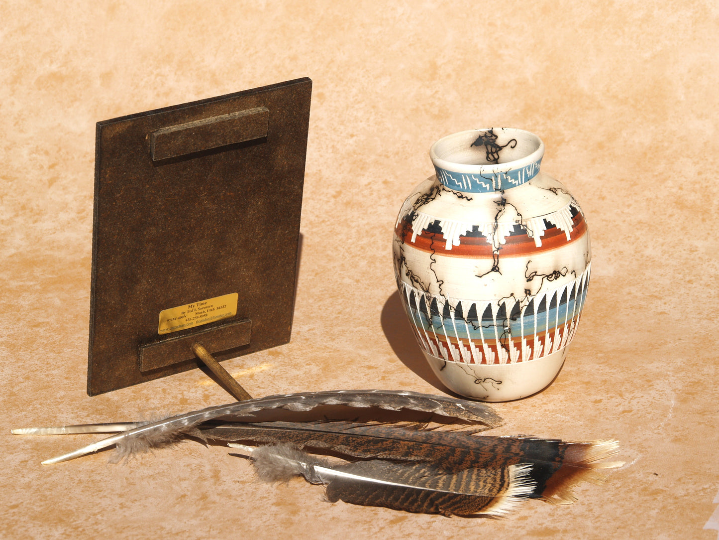 Native American mini art panel displayed with decorative pottery and feathers on a beige surface