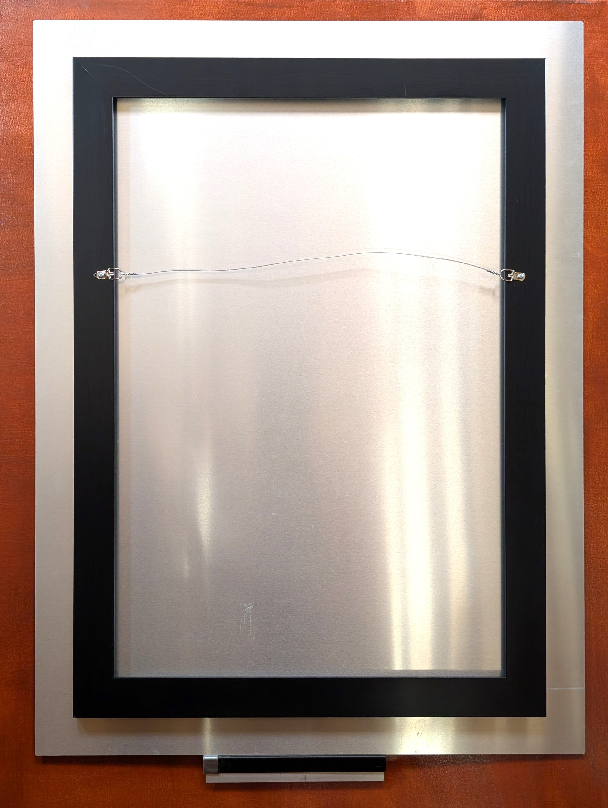 Back view of a Western art metal print by Ted Sorensen featuring hanging wire and black frame
